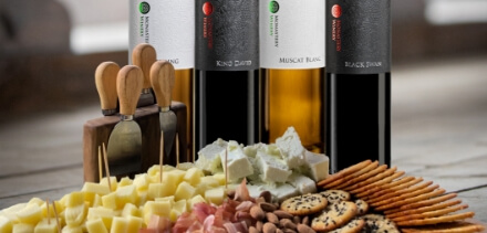 four wine bottles and plate with cheeses and meat